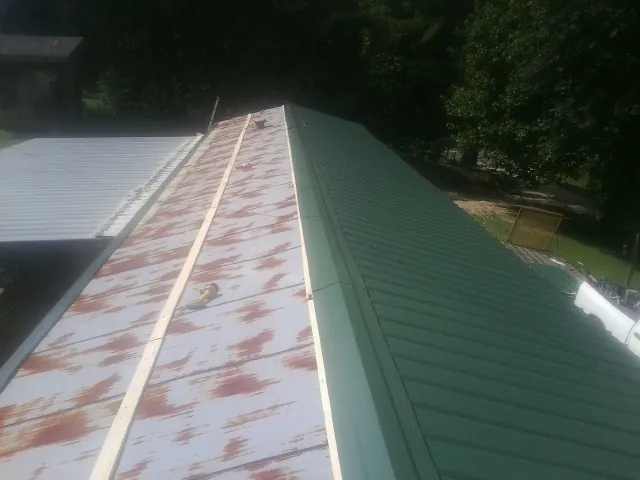 Old rusted panels beside newly installed green metal roofing — Wind Damage Roof Repair by Roofing Brothers in Hampton