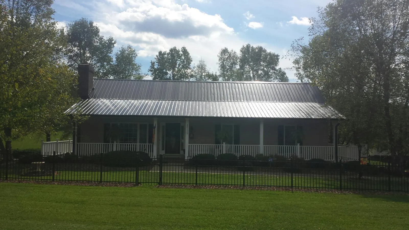 Gray metal roof on a brick ranch with a full width front porch — Gutter Guard Installation work by our crew in Hampton